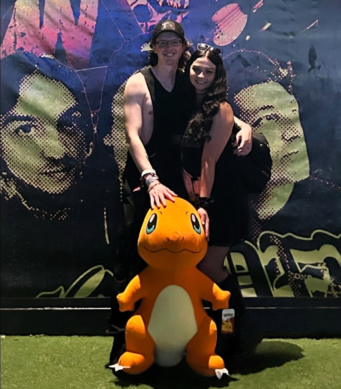 Tristan and a companion posing in front of a colorful mural